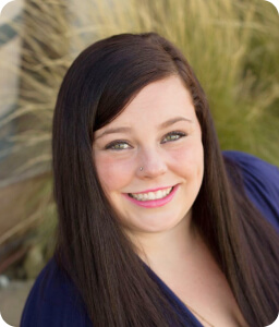 young brunette woman with long hair smiling outside