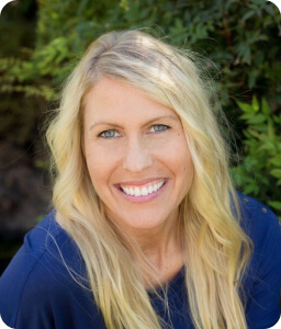 blonde smiling woman wearing blue shirt outdoors