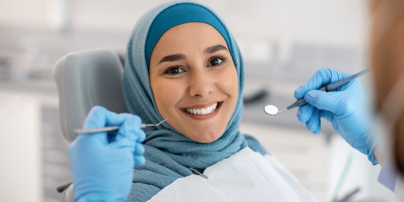 woman smiling at the dentist with dental tools near her mouth