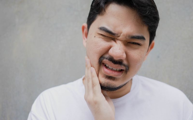 man who's holding his jaw in pain