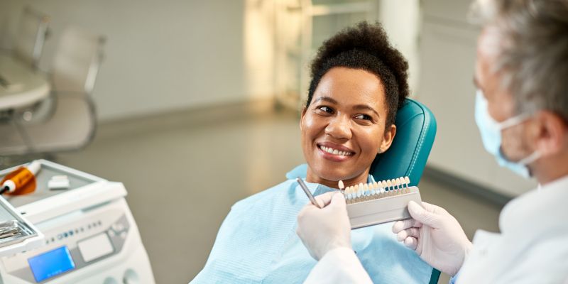 young woman picking out her porcelain veneer shade at the dentist