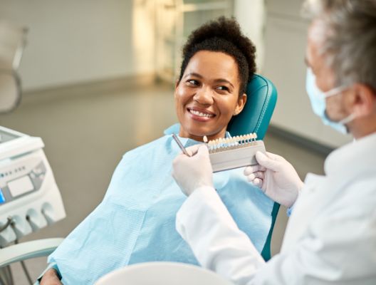 young woman picking out her porcelain veneer shade at the dentist