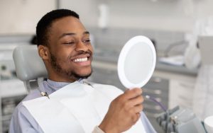 man looking at his smile in a hand mirror