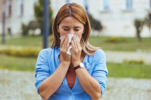 woman blowing her nose into a tissue 