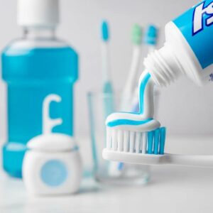 close-up-of-toothpaste-being-squeezed-onto-a-toothbrush-with-dental-care-items-in-the-background